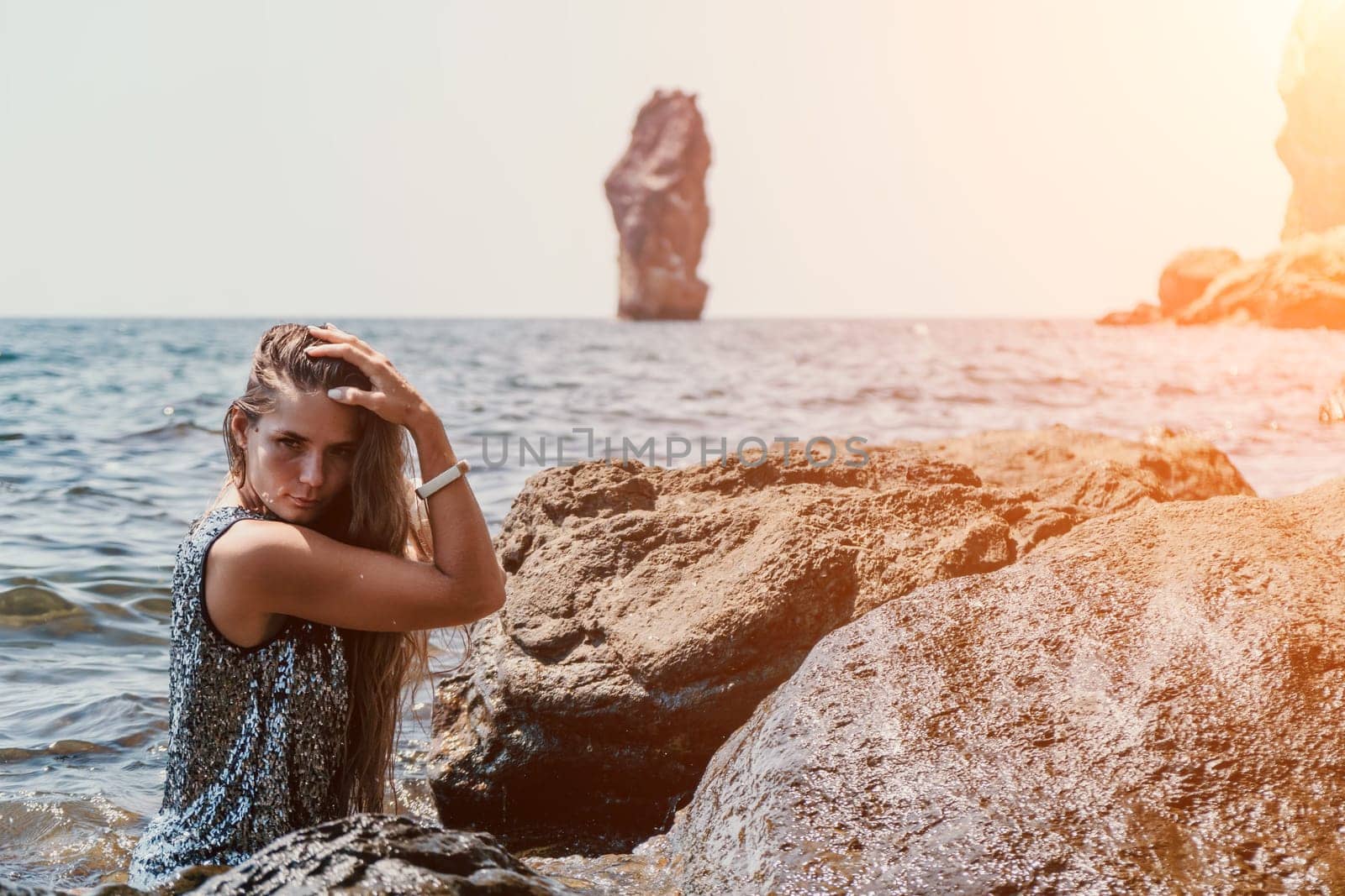 Woman travel sea. Young Happy woman in a long red dress posing on a beach near the sea on background of volcanic rocks, like in Iceland, sharing travel adventure journey