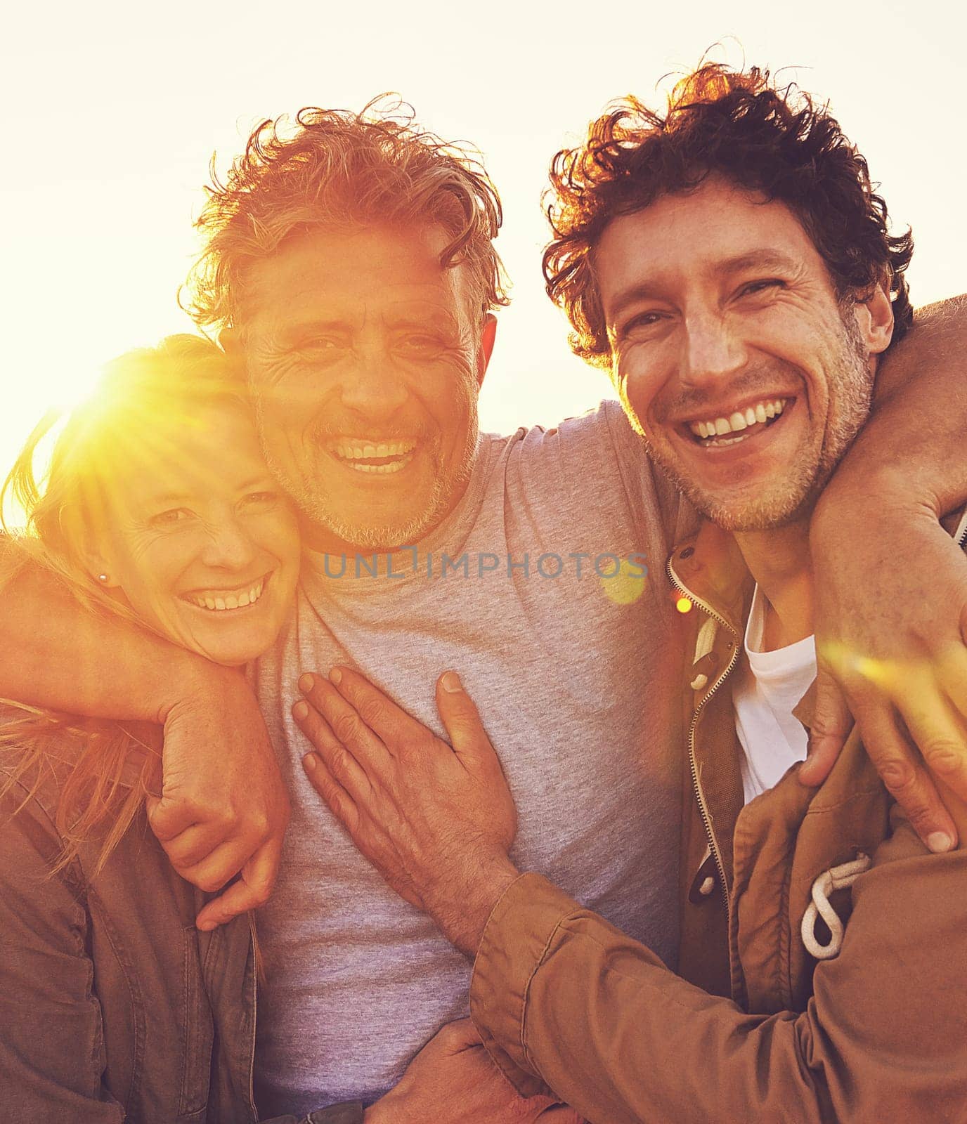 Sunset, hug and senior parent with children for adventure, hiking and walking outdoors. Family, travel and mature father with man and woman embrace on holiday, vacation and weekend together in nature.