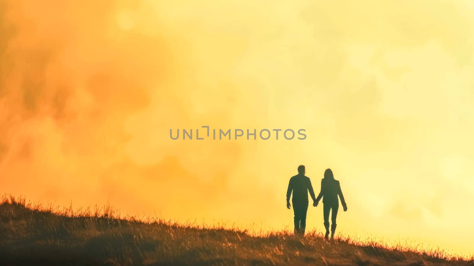Romantic pair holds hands against a vibrant sunset background on a hill