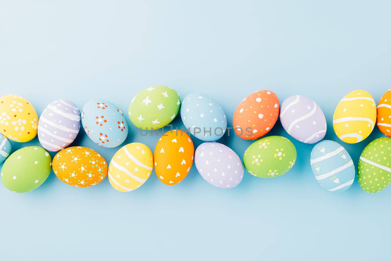 Overhead easter eggs isolated on blue background with copy space, Funny decoration, Happy Easter Day greeting card, Creative composition banner web design holiday background, flat lay top view