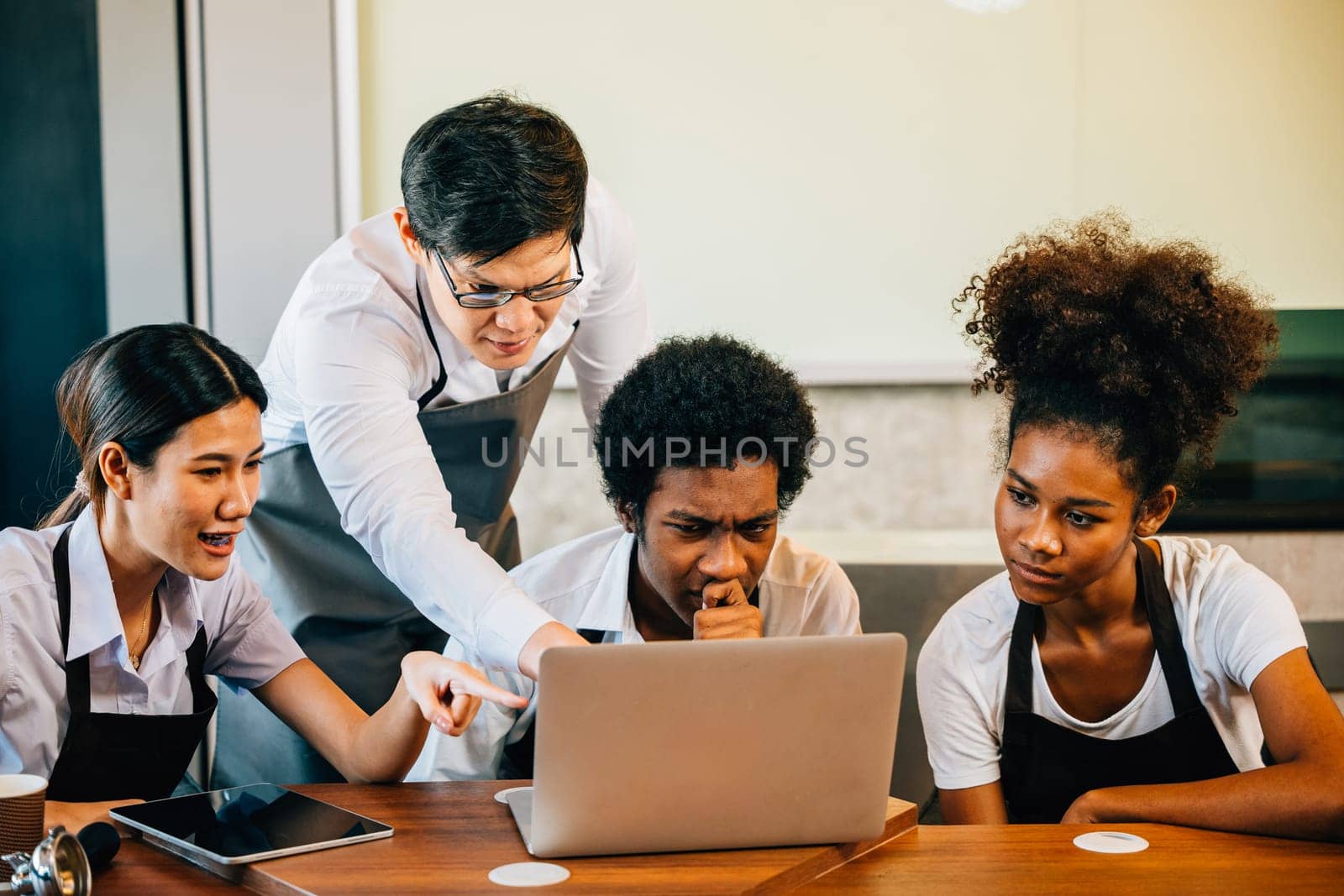 Young entrepreneurs find joy fun pride in the coffee shop business. Planning managing with laptop brings satisfaction. Baristas owners work together for success teamwork.