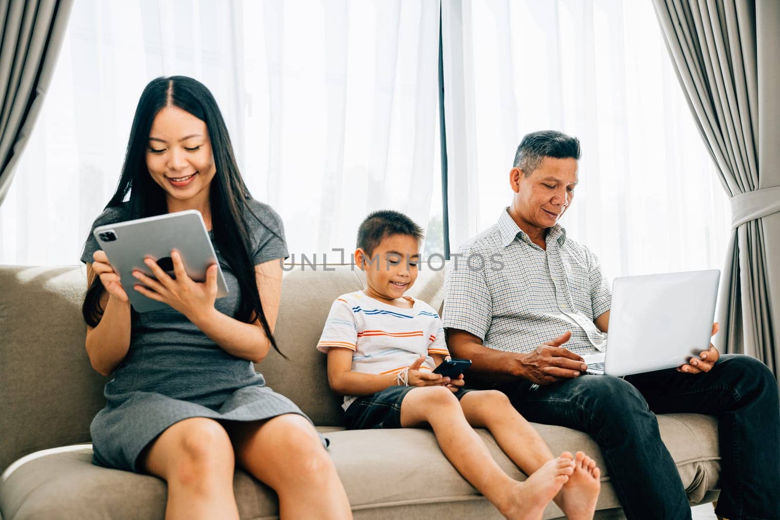 Parents kids engaged with laptops and phones ignoring familial bonding. An Asian family's device dependence portrays the challenges of internet addiction. ignores togetherness