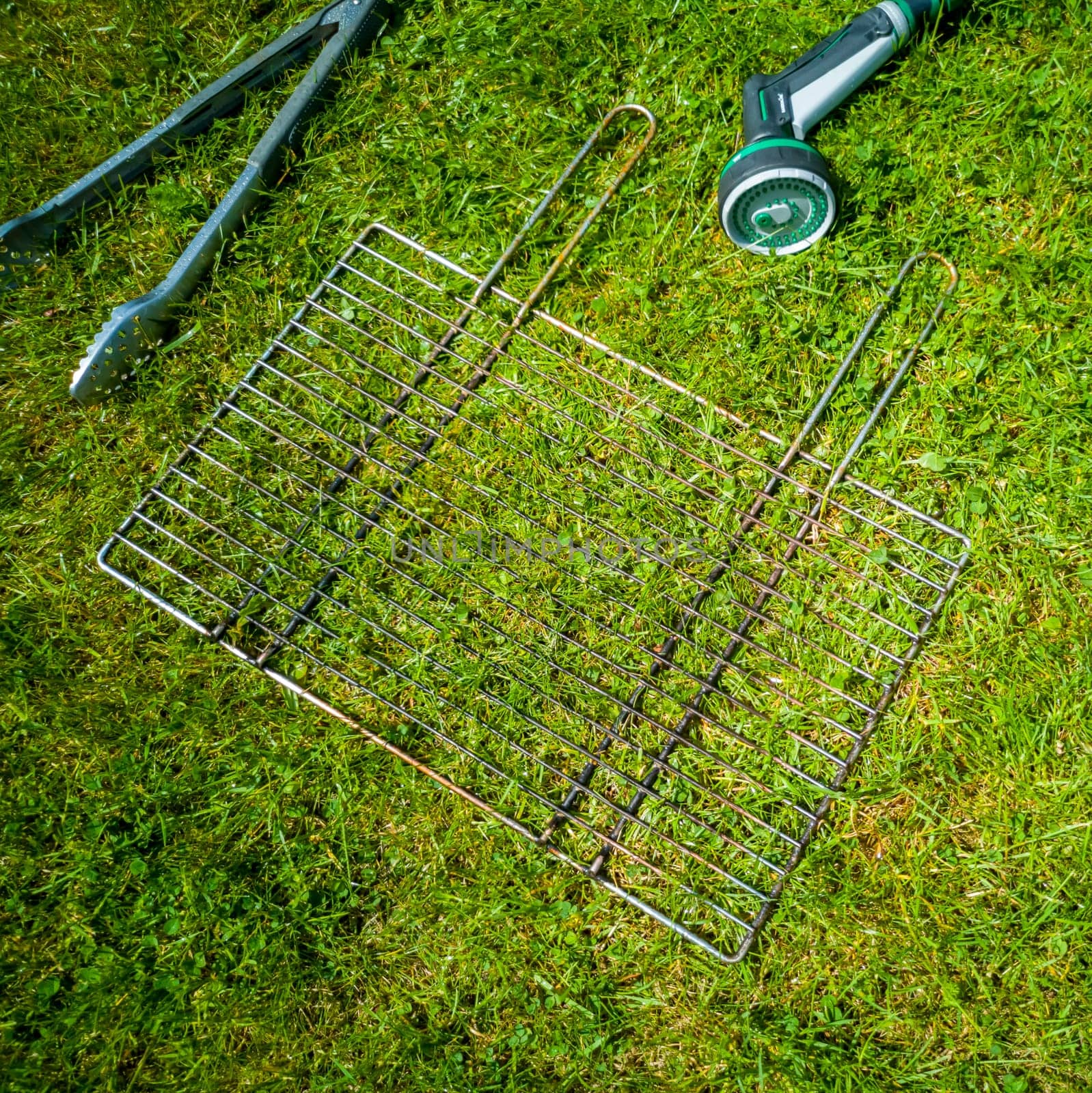 BBQ grillage rost lying on the wet lawn.