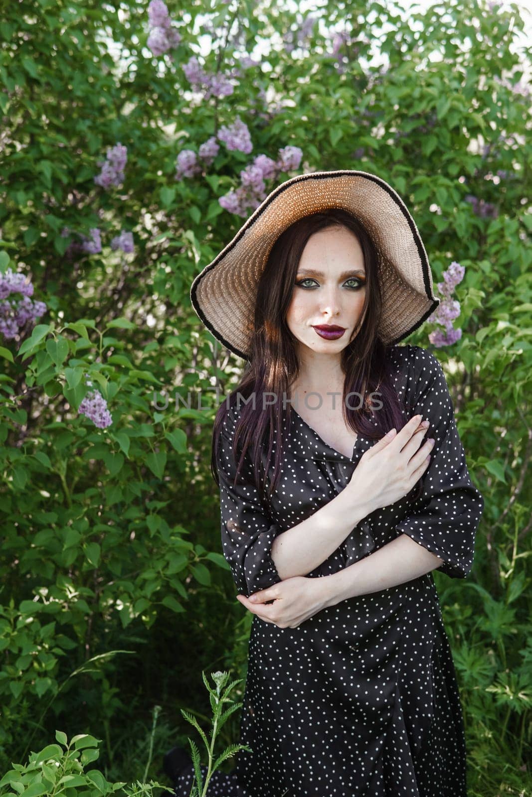 A fashionable girl with dark hair, a spring portrait in lilac tones in summer. Bright professional makeup