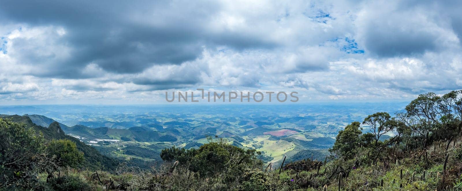 Scenic hilly terrain with lush flora under a cloudy sky.