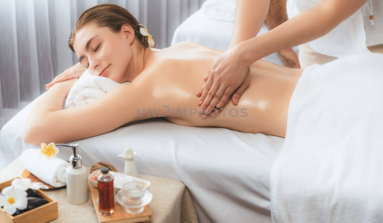 Caucasian couple customer enjoying relaxing anti-stress spa massage and pampering with beauty skin recreation leisure in day light ambient salon spa at luxury resort or hotel. Quiescent