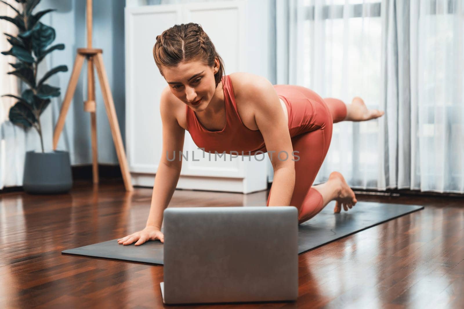 Flexible and dexterity woman in sportswear doing reverse gaiety yoga position by biancoblue