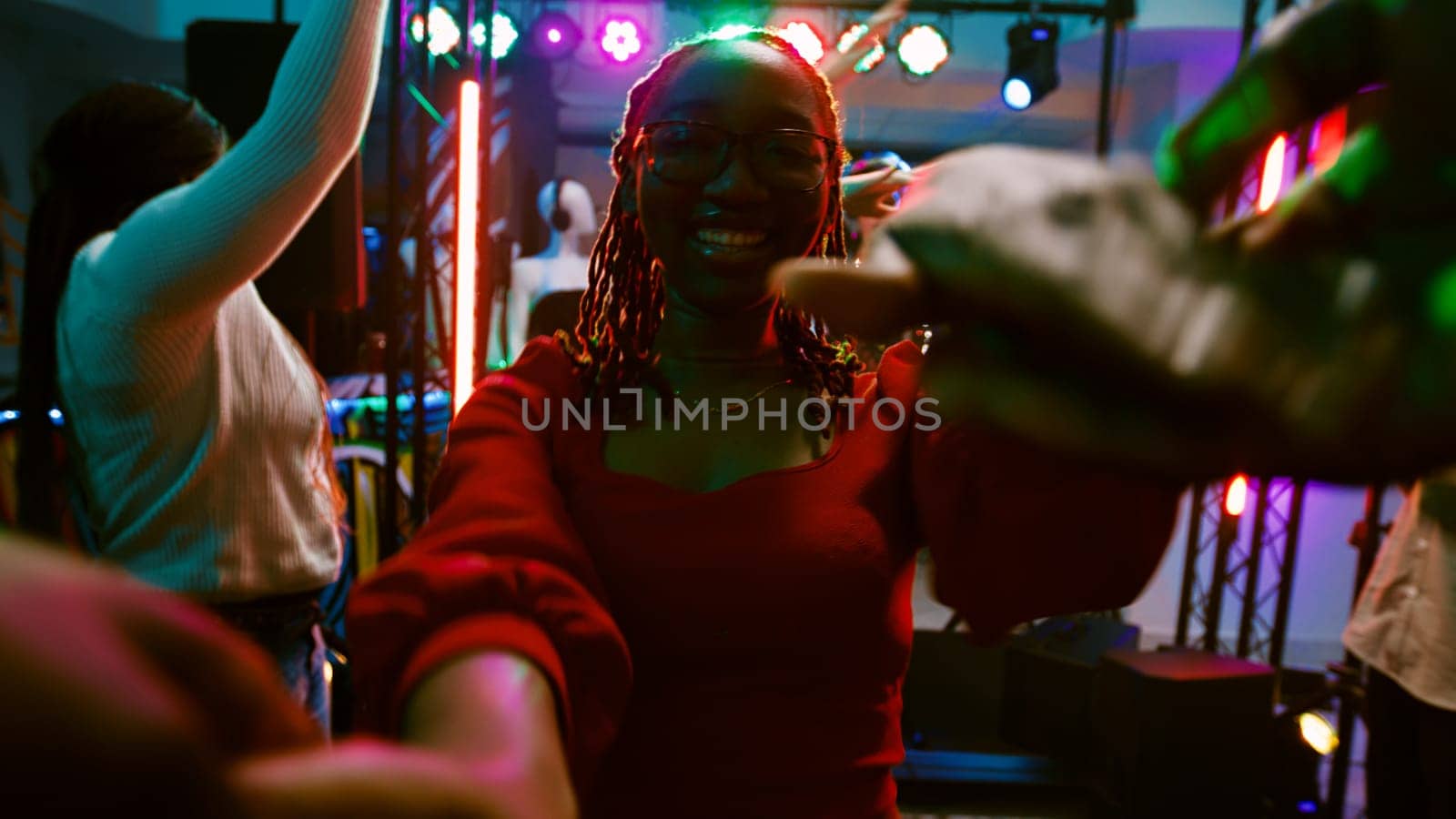 POV of girl dancing with someone at club, enjoying disco party on discotheque dance floor. Group of friends having fun at nightclub listening to electronic music, entertainment. Handheld shot.