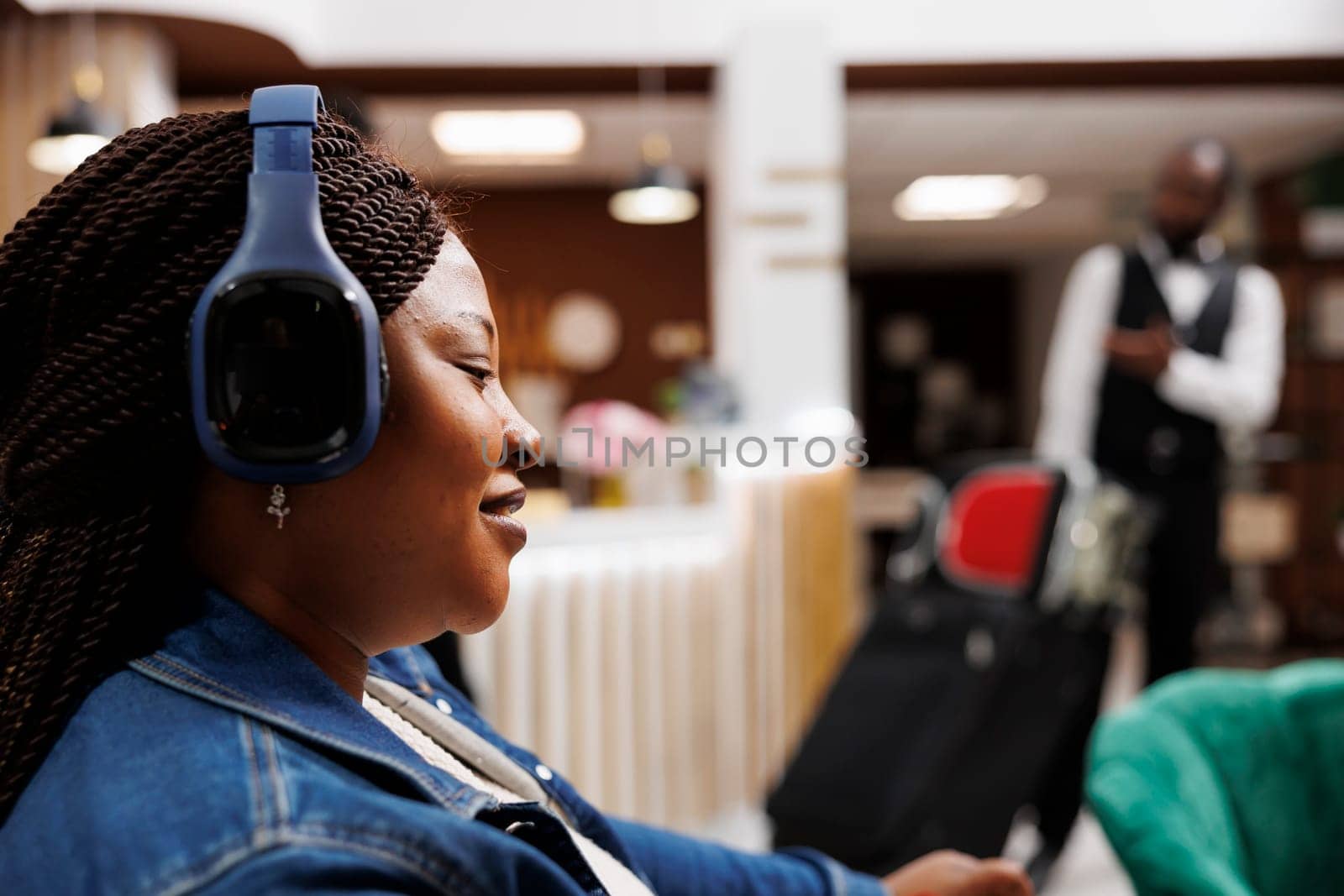 Woman listening to music in hotel lobby by DCStudio