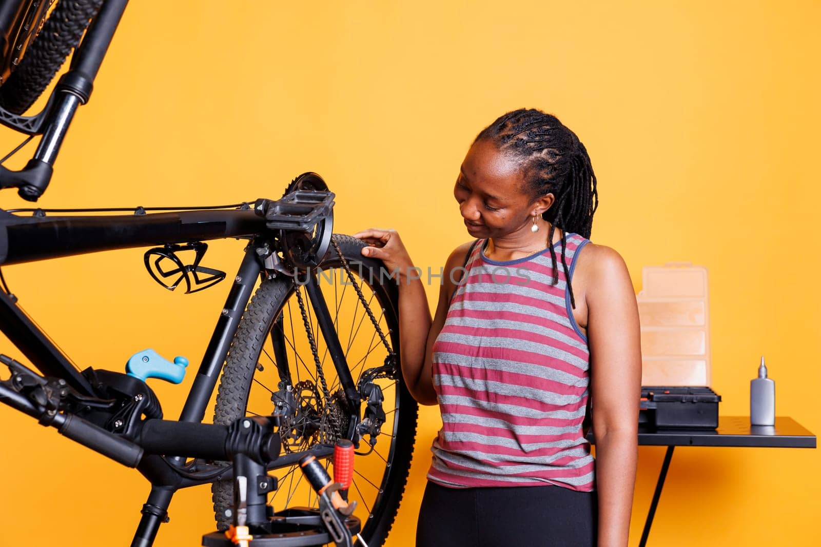 Black woman checking bicycle tire by DCStudio