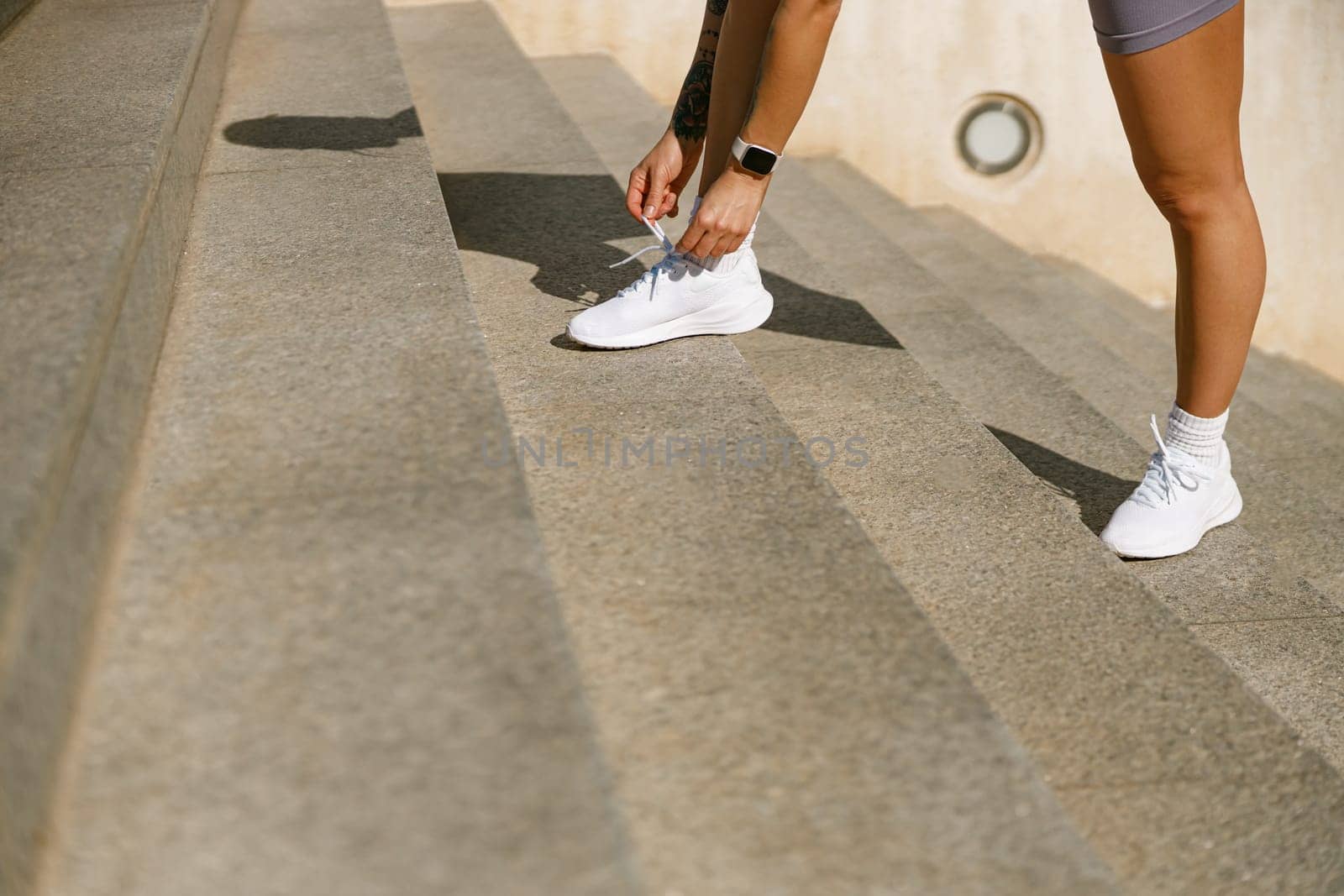 Close up of female athlete preparing for jogging outdoors and tying shoelace