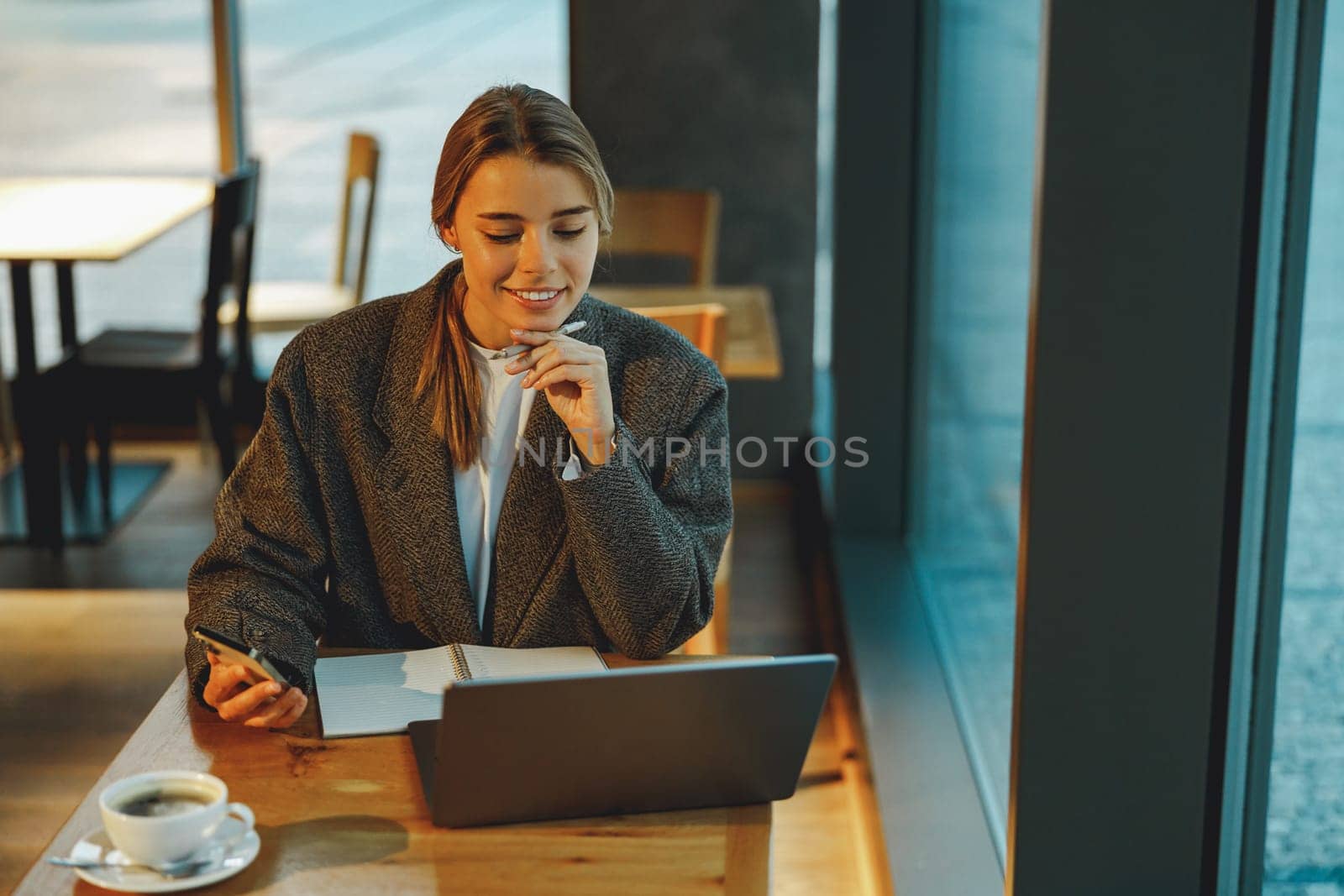 Stylish young female freelancer working on laptop while sitting in cozy cafe