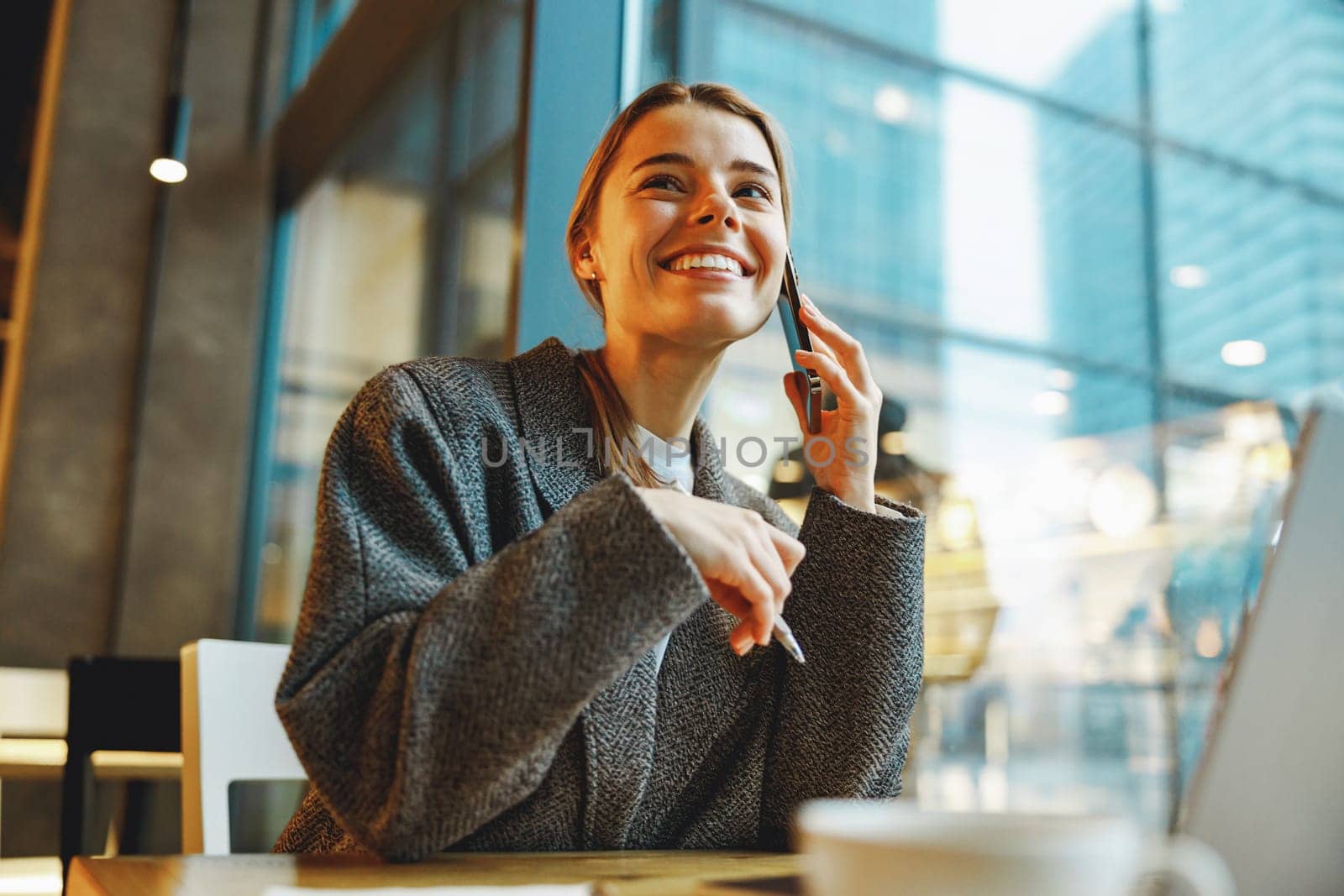 Smiling woman manager talking with client and work on laptop in cafe. Distance work concept