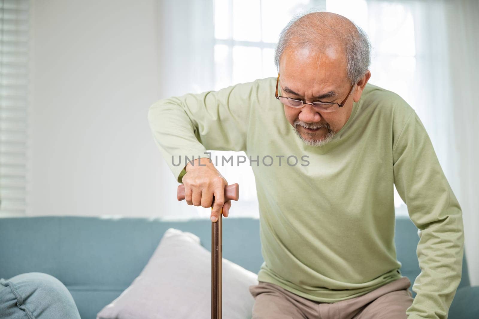 Elderly man suffering from knee pain ache holding handle of cane by Sorapop