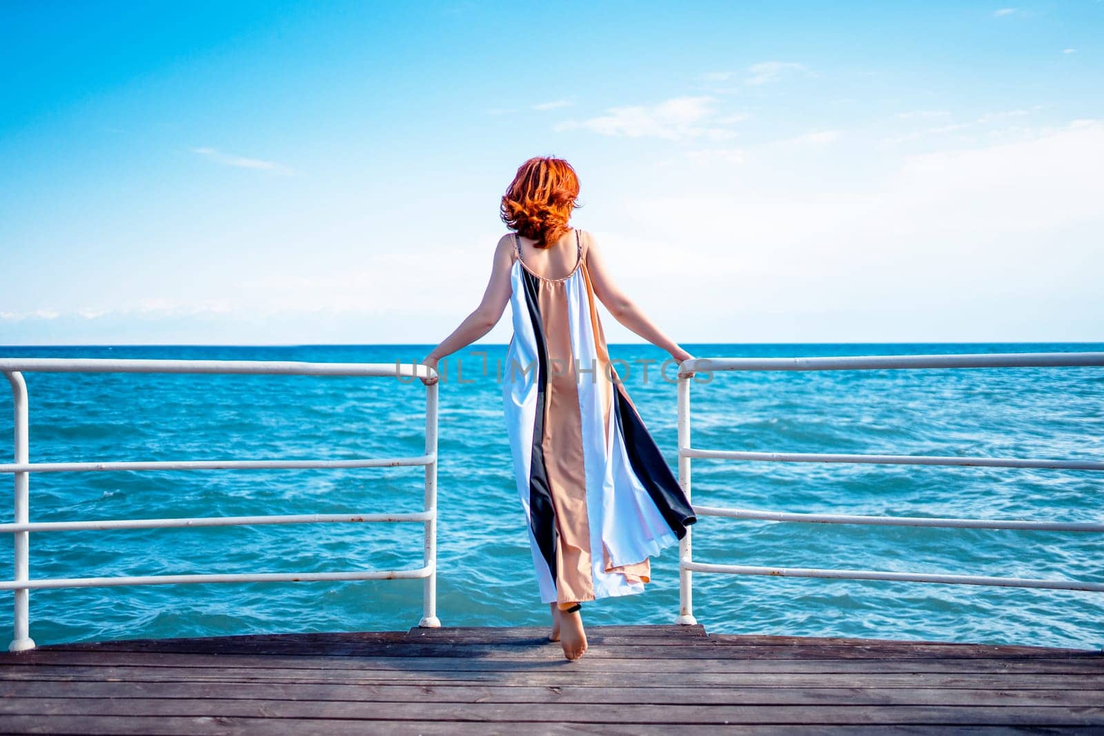Behind girl on pier. Beautiful red head woman on the pier at the sea.