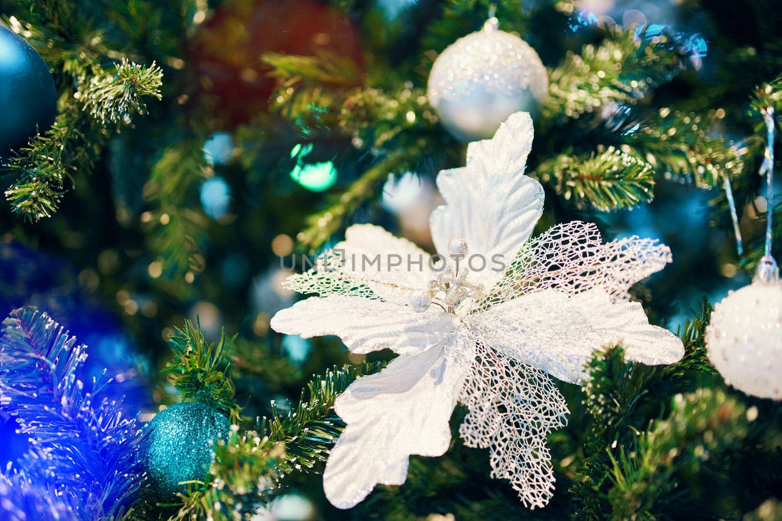 Decorated Christmas tree. Decorated Christmas white flower on blurred, sparkling and fairy backgrounds with Christmas tree.