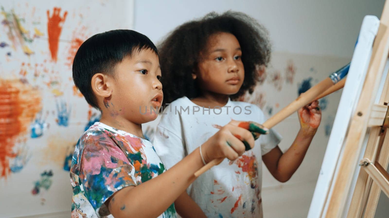 Creative african girl painted or draw canvas together with asian boy. Erudition. by biancoblue