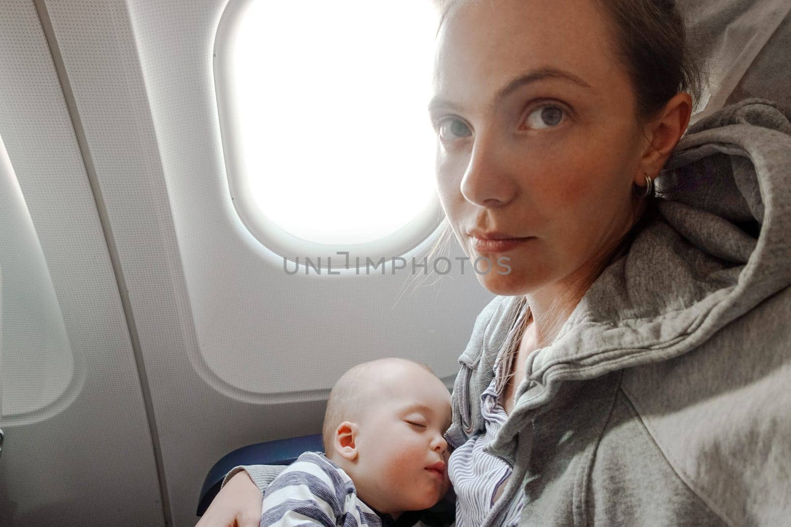 Close-up of adorable baby sleeping on hands of mother while having flight in airplane