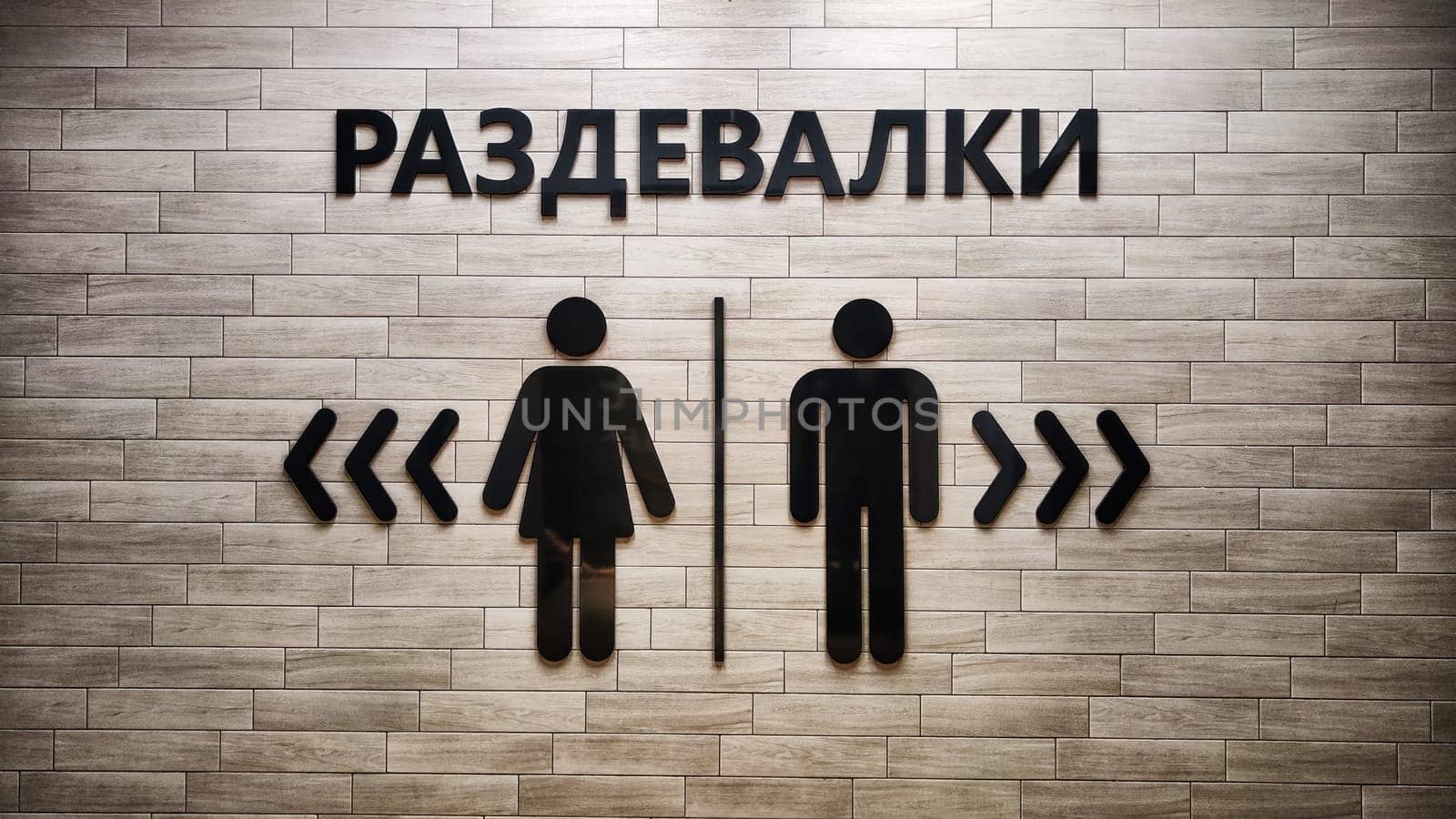 Male and Female Restroom Symbols on Wooden Wall With Directional Arrows. Gender-specific bathroom signs on wood surface