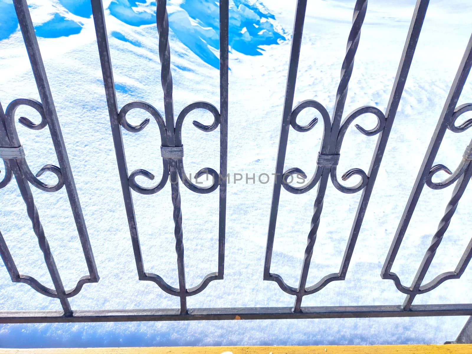 Winter Sunrise Through a Decorative forged Fence. Sunlight piercing through an ornate fence on a snowy spring or winter day