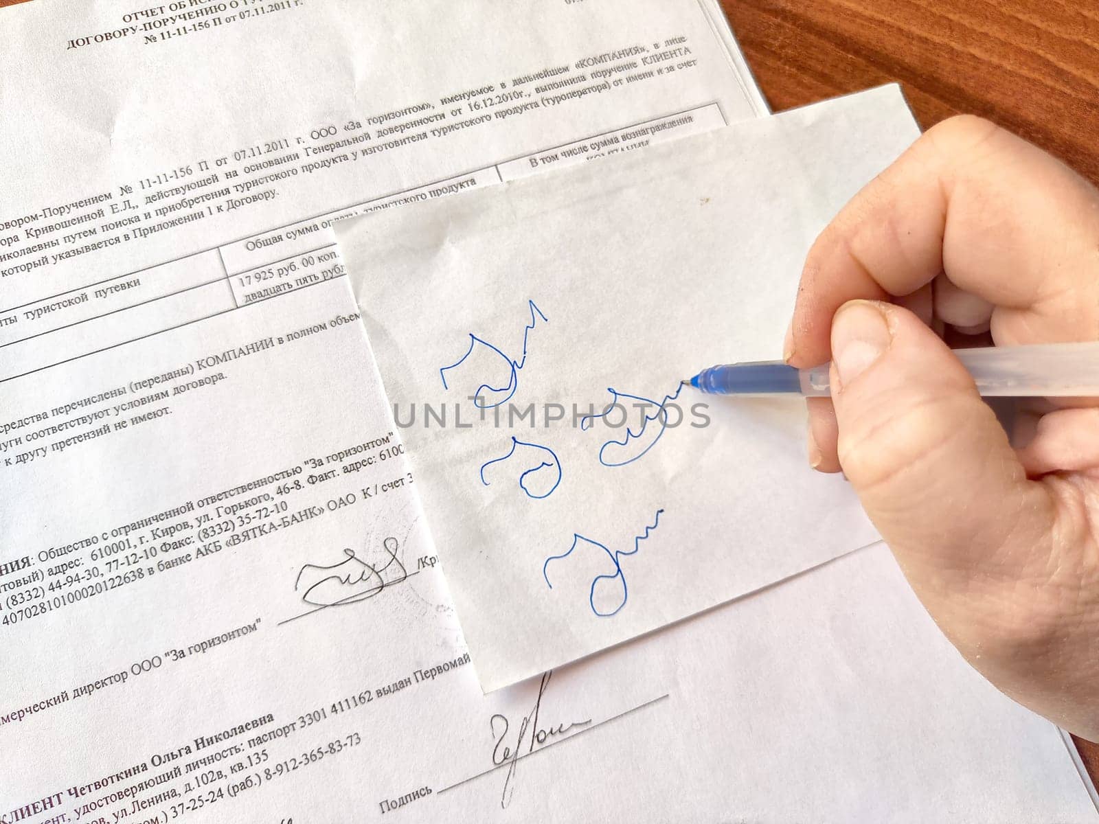 Hand hand of woman with pen meticulously tries to copy a signature from document. Violation of the law. Illegal signature