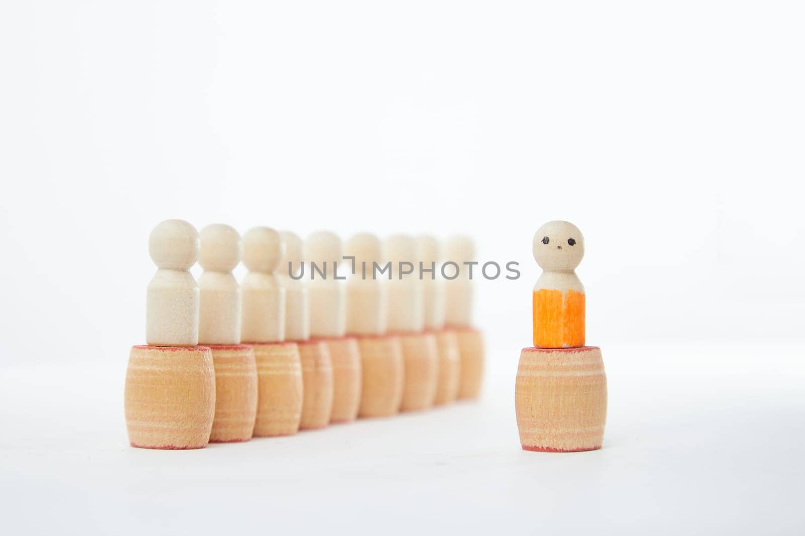 Wooden figurines with a leader and group with partial focus. The concept of distinguishing a leader from the crowd. Sighted, intelligent, different among the blind group