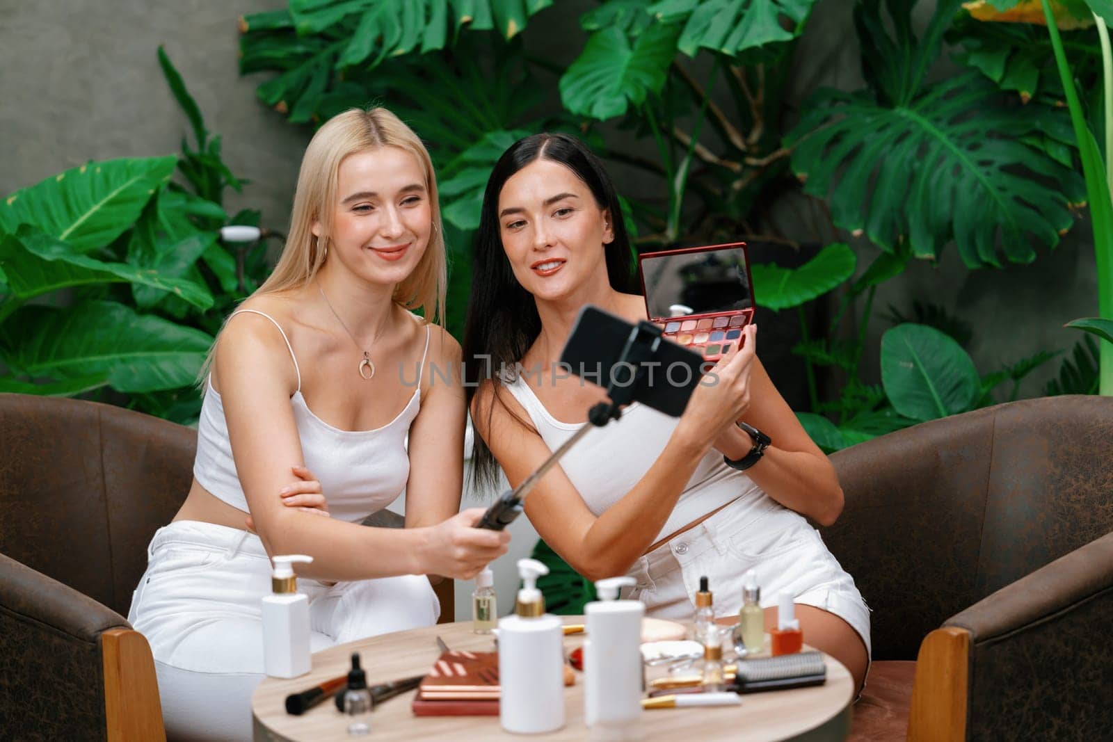 Two beautiful content creator making natural beauty and cosmetic tutorial on green plant garden video. Beauty blogger showing how to beauty care to social medial audience using selfie stick . Blithe