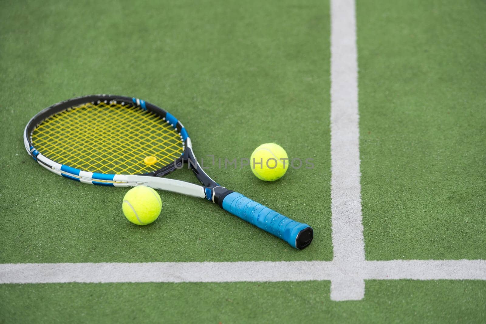 Tennis ball and racket on the ground of sunny outdoor grass tennis court. Summer, healthy lifestyle, sport and hobbies. High quality photo