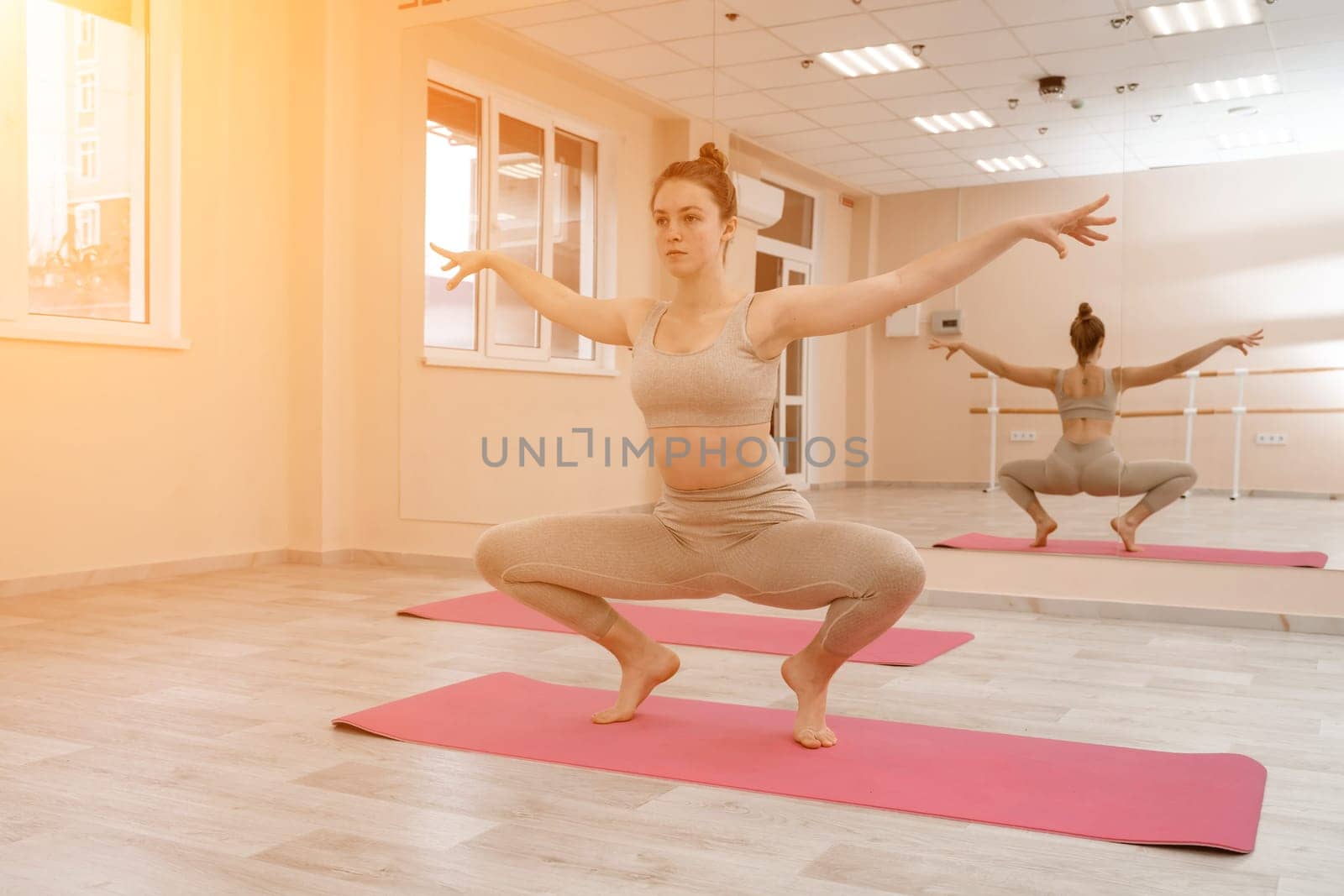 Girl does yoga. Young woman practices asanas on a beige one-ton background