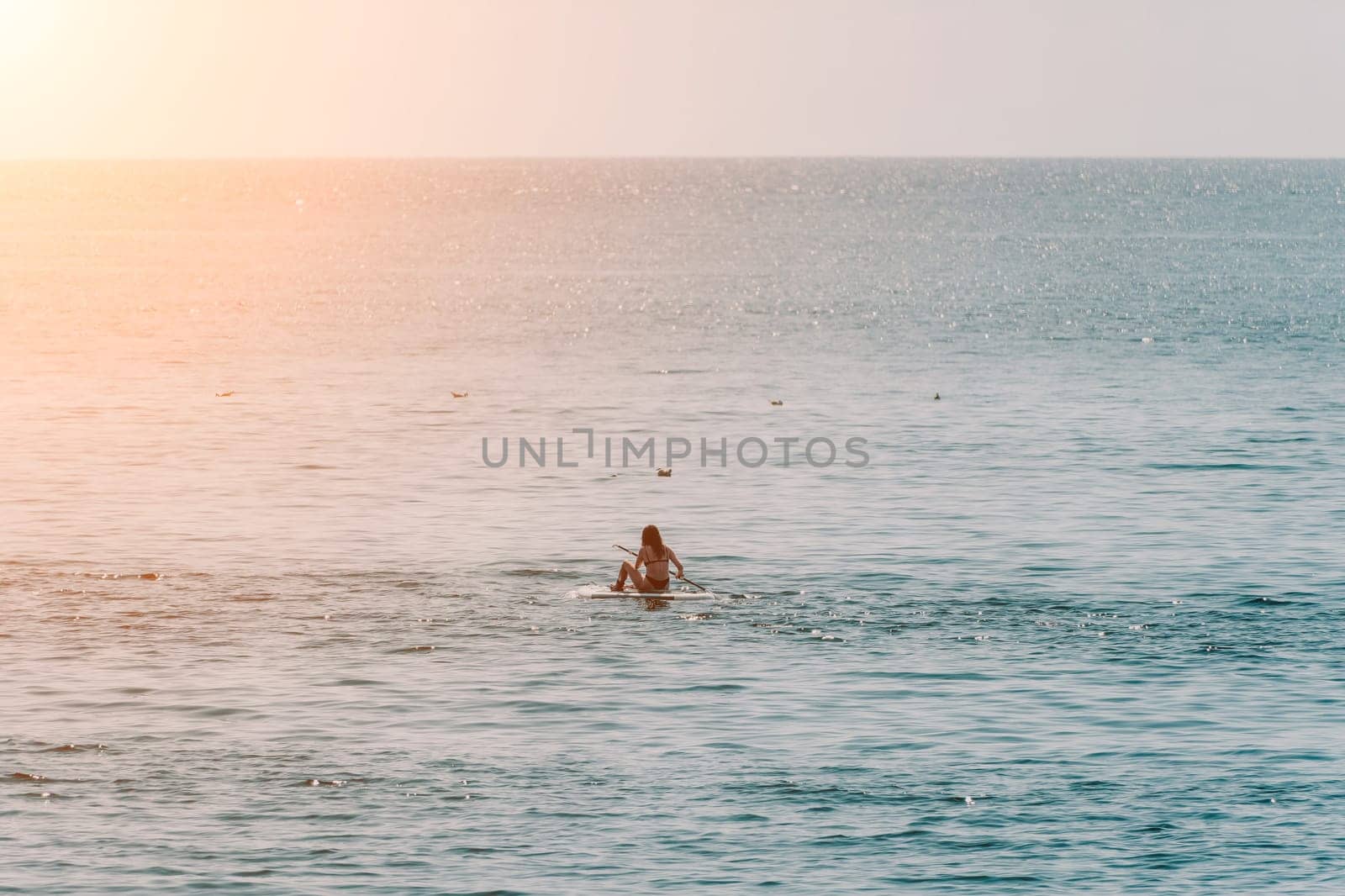 Sea woman sup. Silhouette of happy positive young woman in bikini, surfing on SUP board, confident paddling through water surface. Idyllic sunset. Active lifestyle at sea or river. Slow motion. by panophotograph