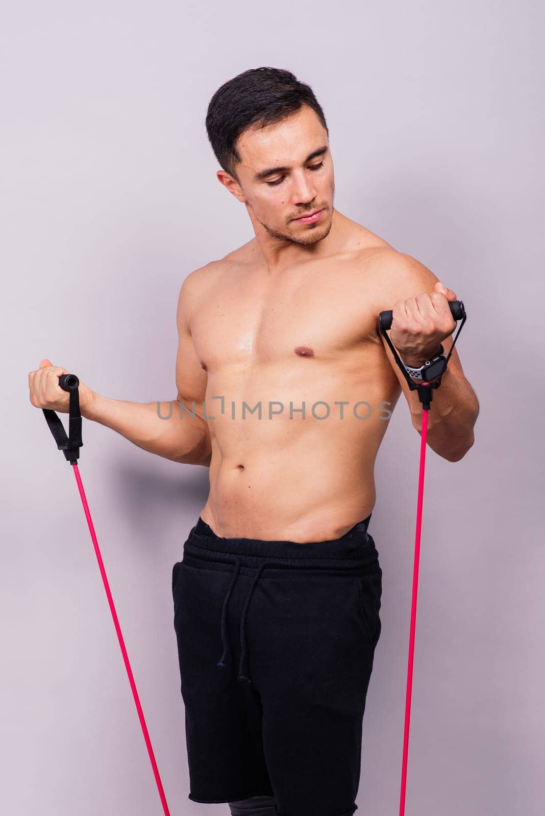 Young handsome man during workout with resistance rubber bands. Shoulder lateral raise exercise.