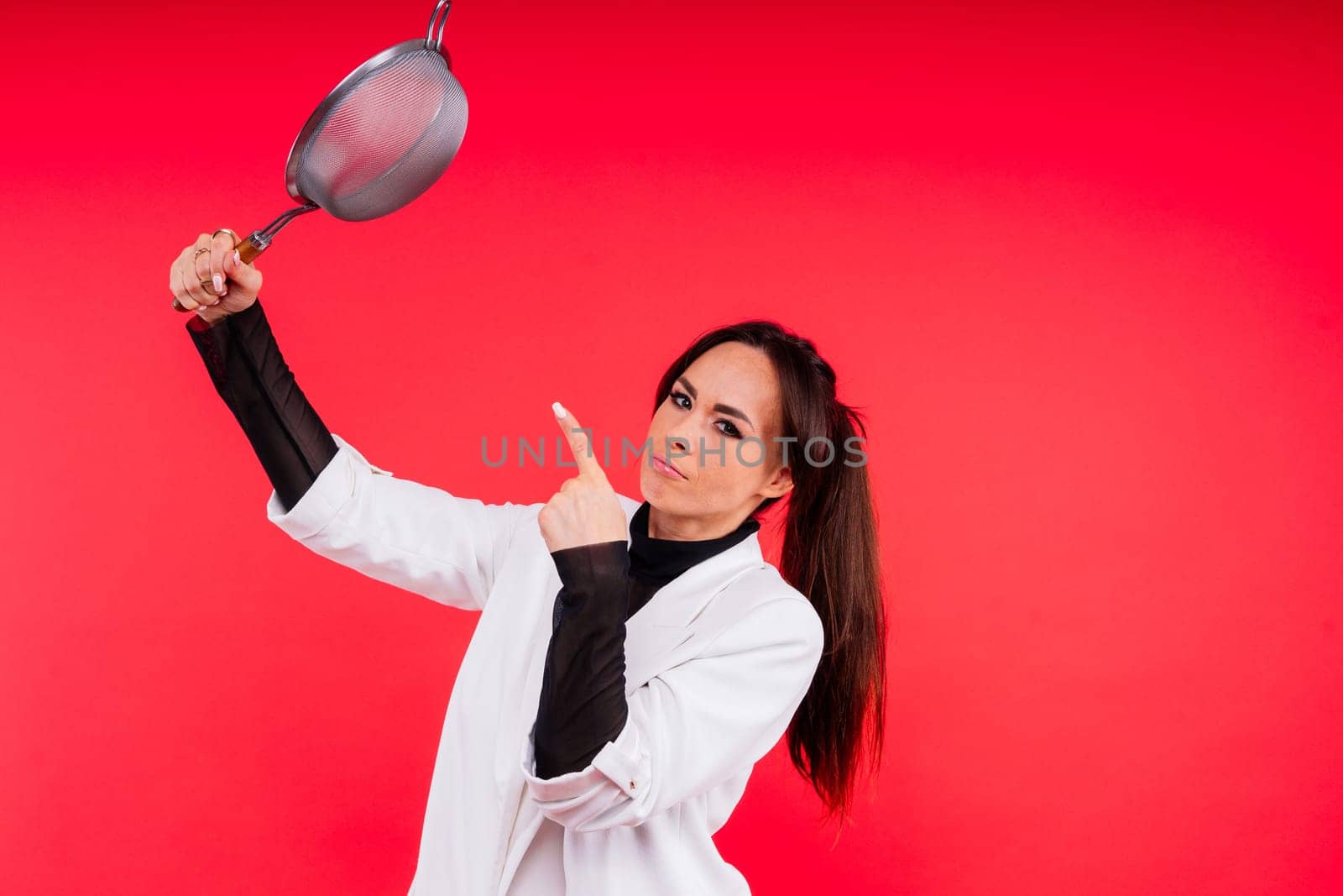 Female with metal sieve for sifting flour in a female hand on red and white background. by Zelenin