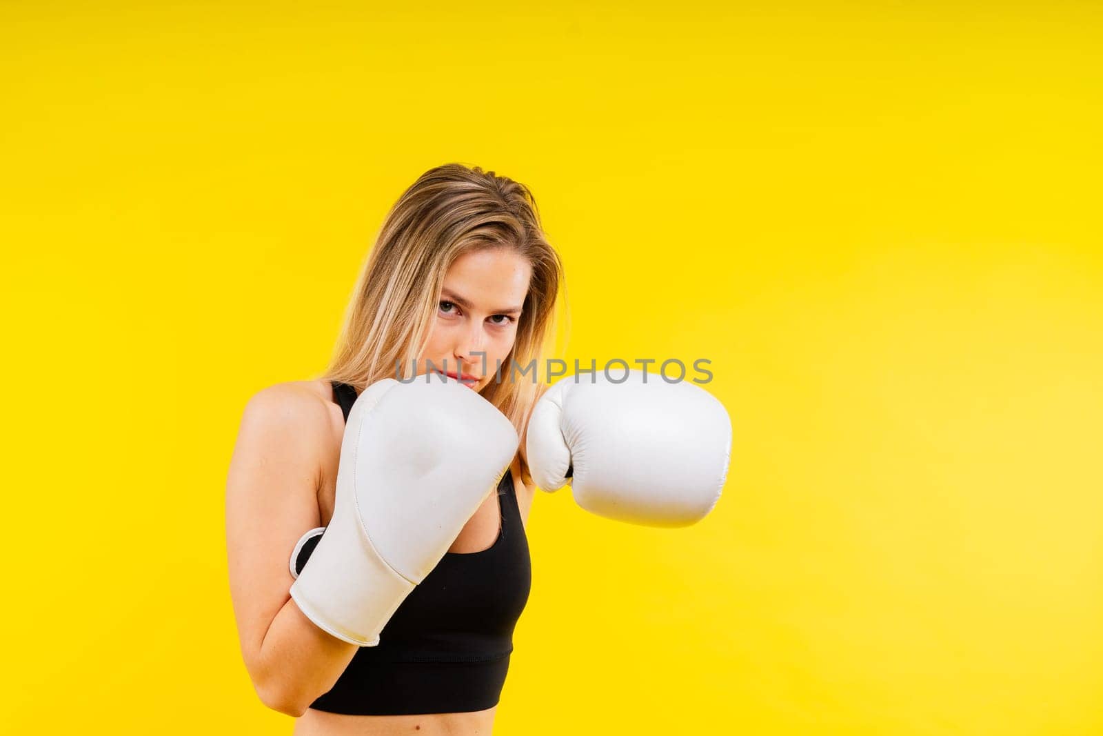 Female boxer hitting at a boxing studio. Woman in gloves training hard. by Zelenin