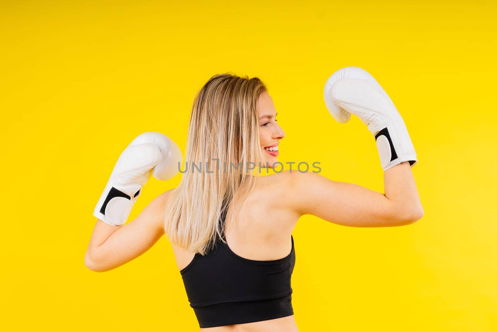 Female boxer hitting at a boxing studio. Woman in gloves training hard. by Zelenin