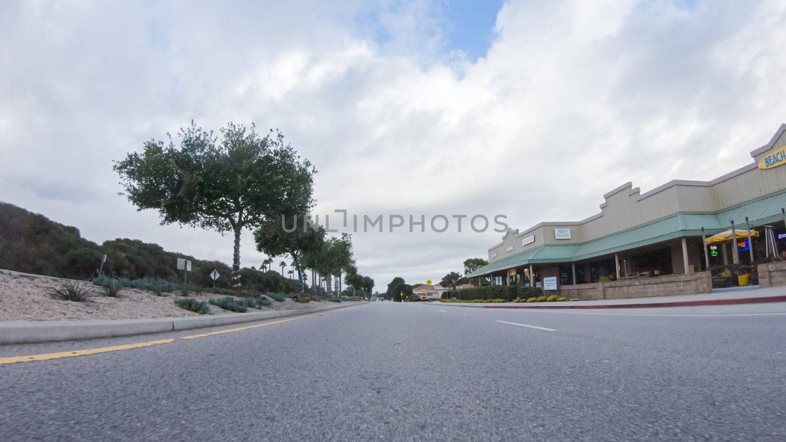 Santa Maria, California, USA-December 6, 2022-Vehicle navigates the streets of Morro Bay, California, during a cloudy winter day. The atmosphere is moody and serene as the overcast sky casts a soft light on the charming buildings and quiet streets of this coastal town.