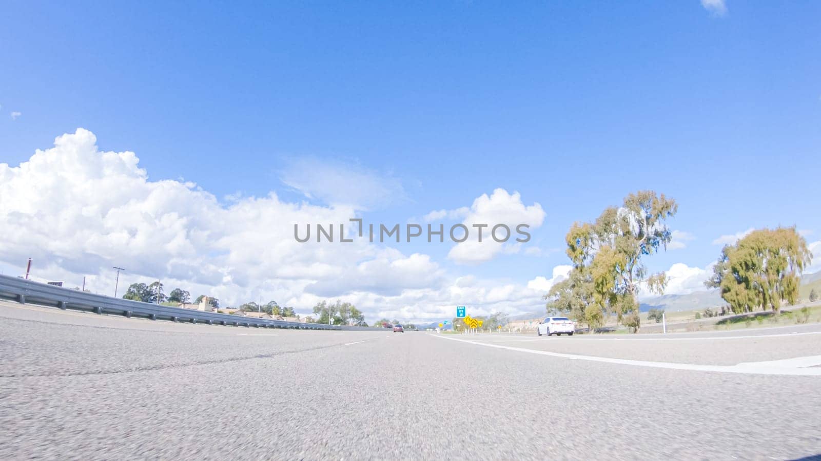 Santa Maria, California, USA-December 6, 2022-On a crisp winter day, a car cruises along the iconic Highway 101 near San Luis Obispo, California. The surrounding landscape is brownish and subdued, with rolling hills and patches of coastal vegetation flanking the winding road.