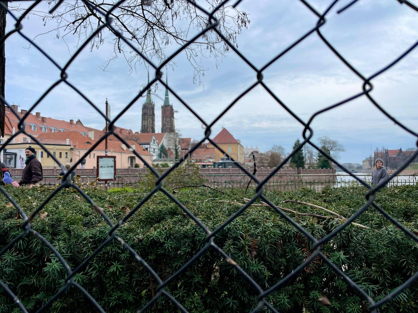 A glimpse of the city through the fence of woven metal mesh. High quality photo