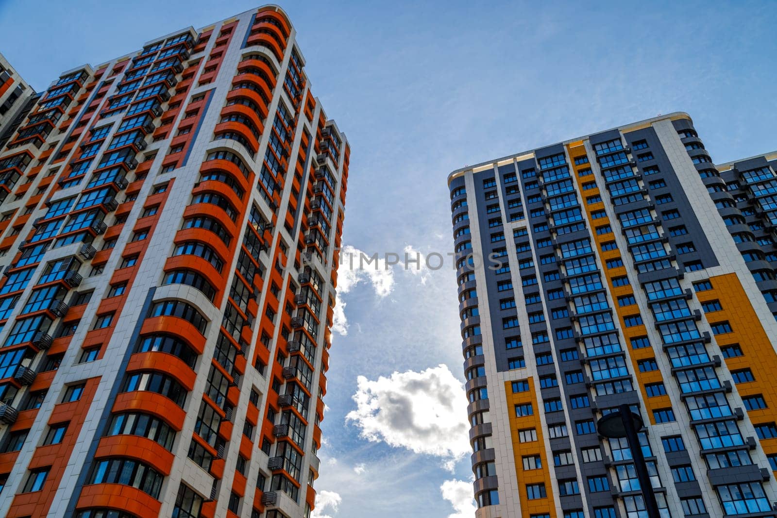 freshly built high rise apartment buildings on blue sky background with white clouds, low angle view