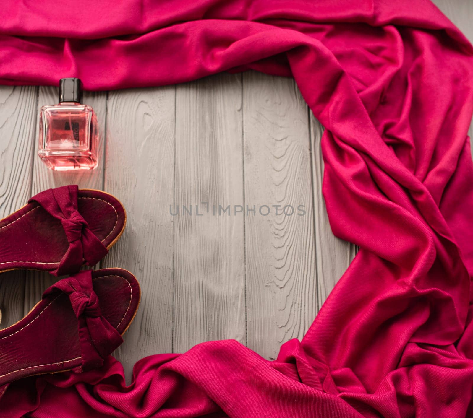 burgundy sandals wedge shawl shoes and bottle pink perfume. Summer background template mockup copy free space pattern colorful composition sample text. Top view above grey wooden background flat lay