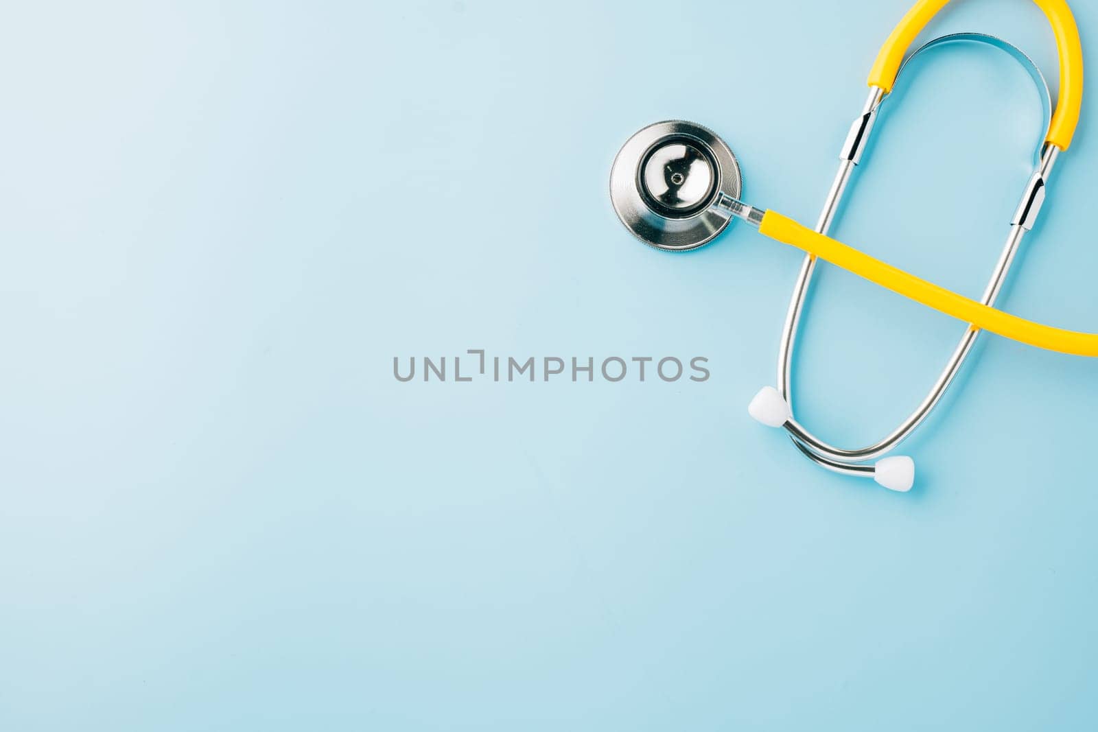 Top view yellow medical stethoscope isolated on blue background with copy space for you text, Doctor equipment, healthcare and medical, Doctor Day and World cancer day Concept