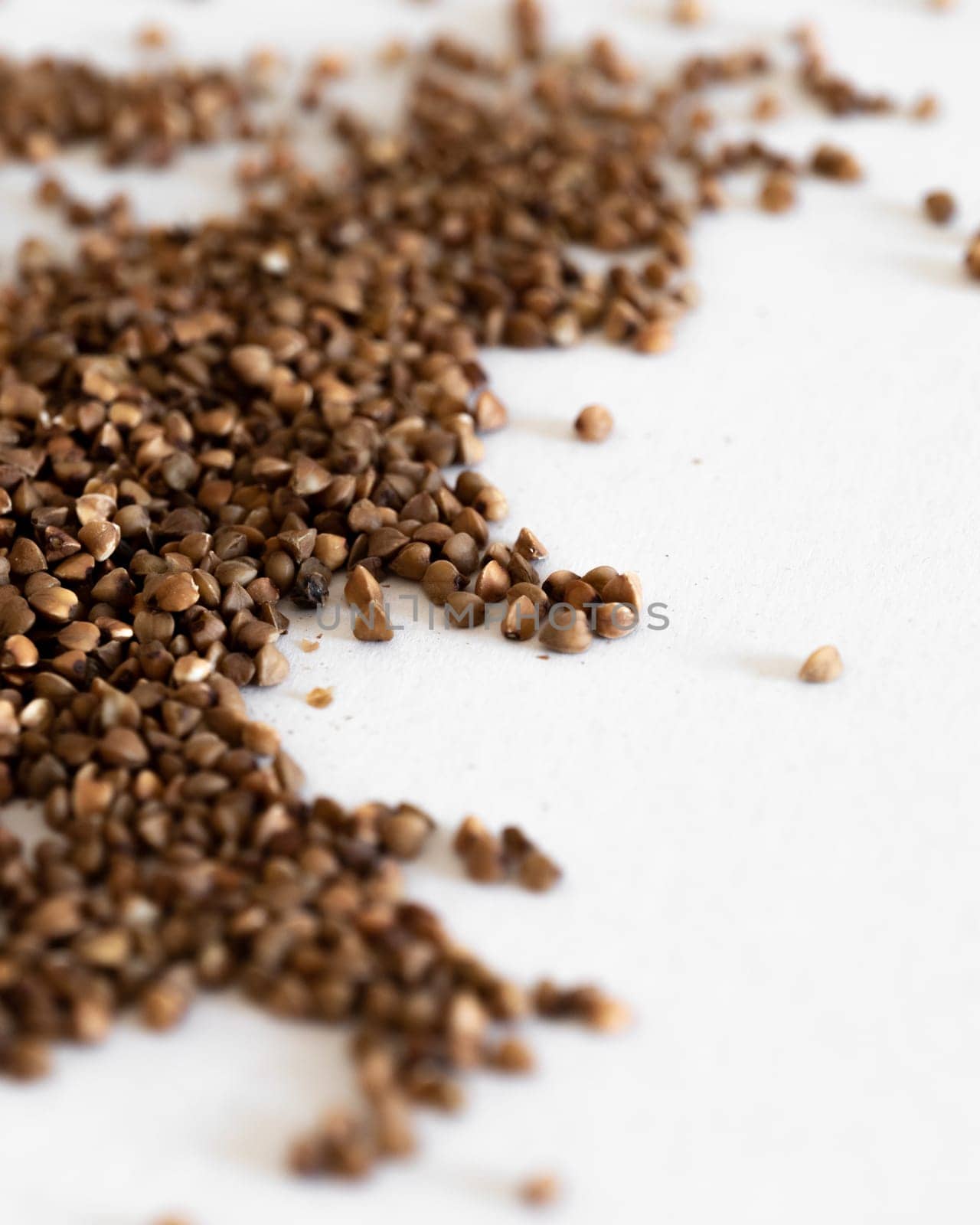 A Pile Of Brown Grains of buckwheat On A White Surface by apavlin