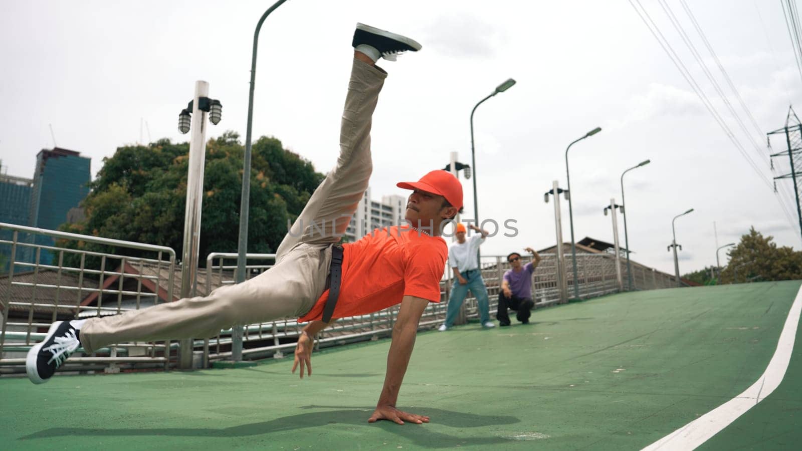 Young happy hipster perform break dancing or foot step with friend moving to hiphop music together. Skilled dancer doing freeze pose and waving hand. Modern lifestyle. Outdoor music 2024. Sprightly.