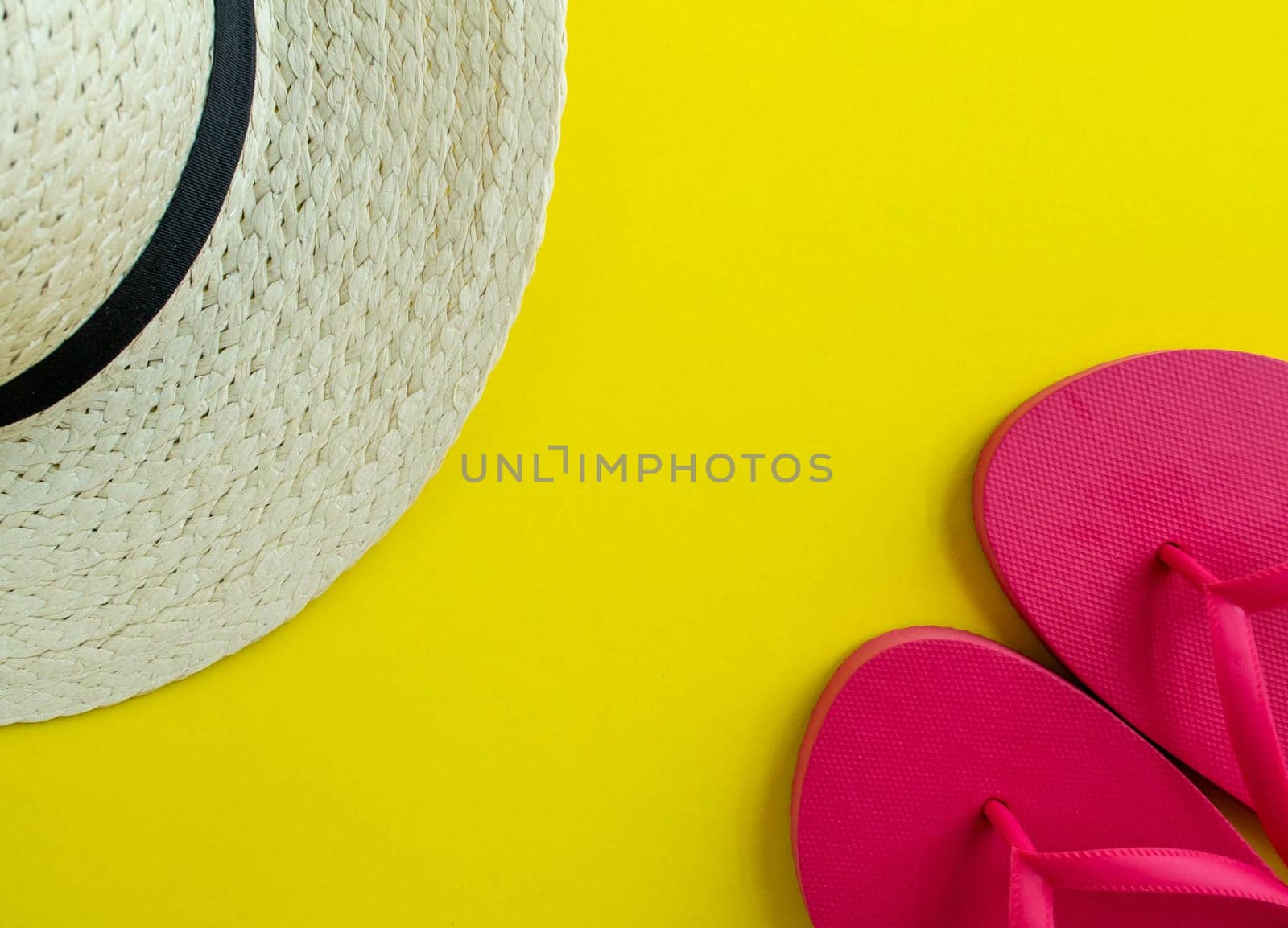 Flatlay, summer vacation. Hat and sandals on a yellow background. Background for advertising.