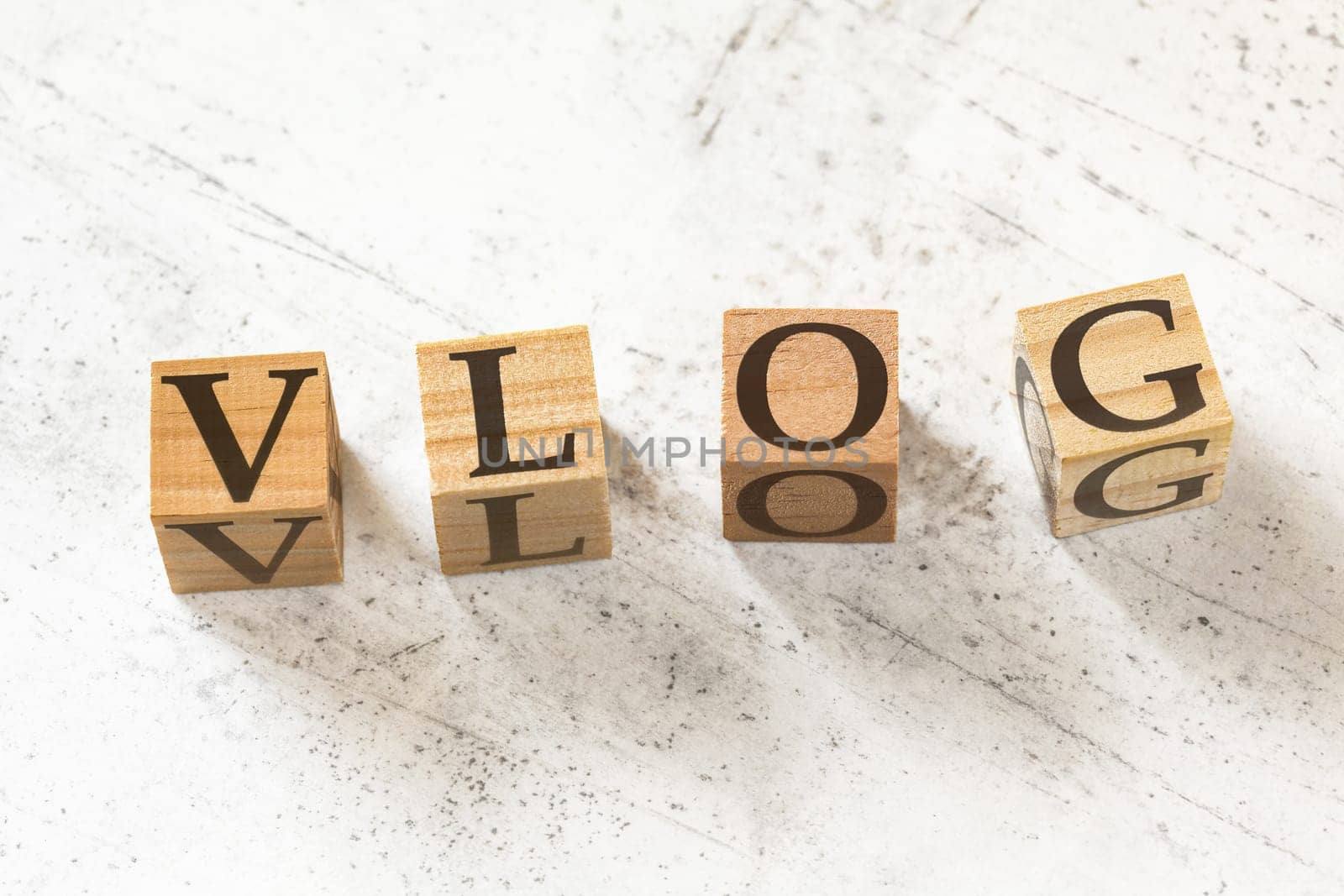 Four wooden cubes with word VLOG (meaning Video Blog) on white working board. by Ivanko