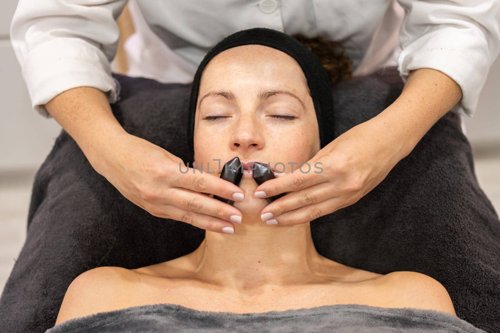 Woman having facial massage with mineral stones in salon by javiindy