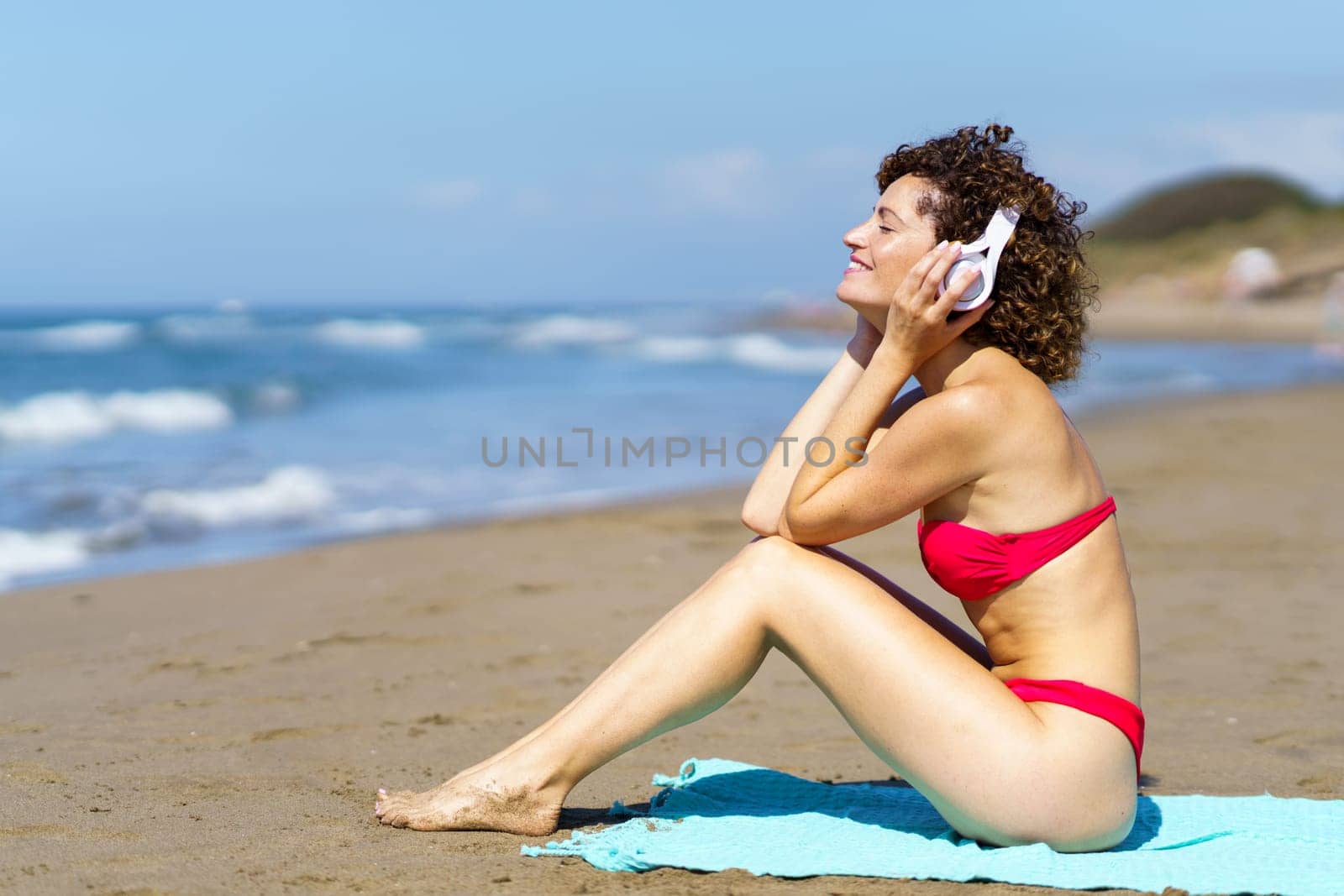 Happy woman listening to music on sandy beach by javiindy