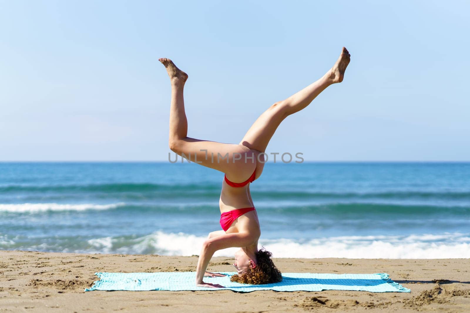 Slim lady performing yoga on coastline by javiindy