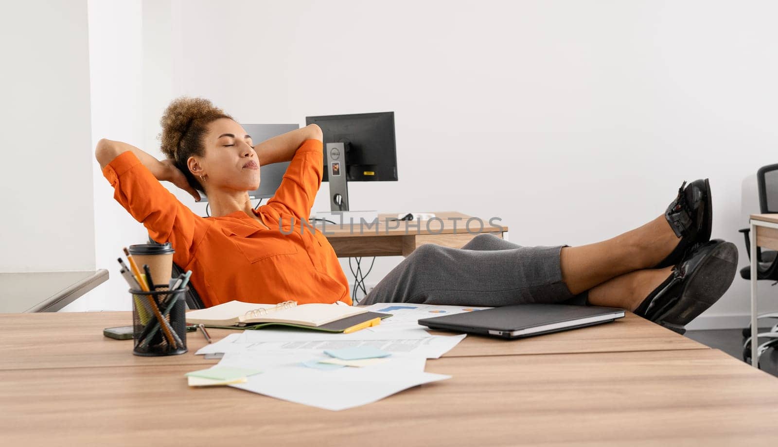 Young busy African business woman executive working on laptop making call at office.