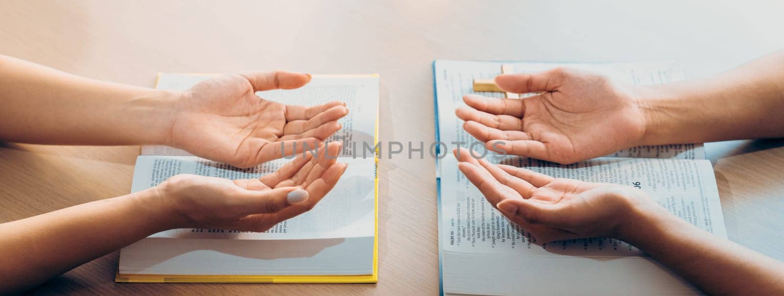 Two believer praying together on holy bible book faithfully with wooden cross placed at wooden church. Concept of hope, religion, faith, christianity and god blessing. Facing hand. Burgeoning.