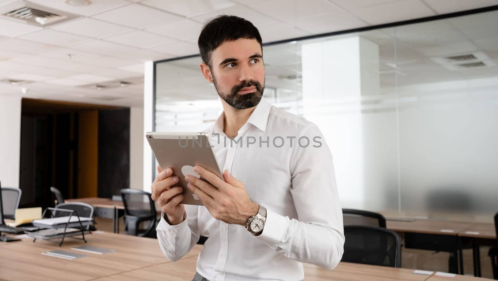 Smiling mature businessman holding a smartphone in an office. High quality photo